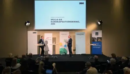 Två talare på scenen vid ett event.