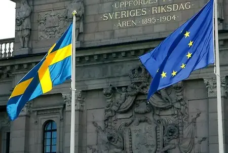 Svenska flaggan och EU-flaggan framför riksdagsbyggnaden.