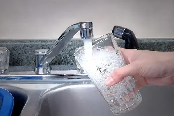 Fyller på ett glas vatten under en vattenkran i ett kök.
